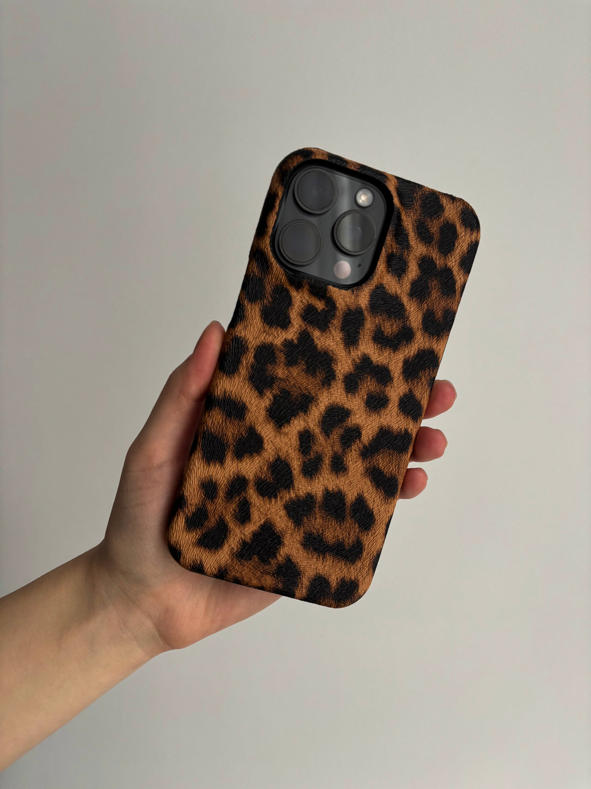 Леопардовий чохол Leopard на iPhone у руці на світлому тлі