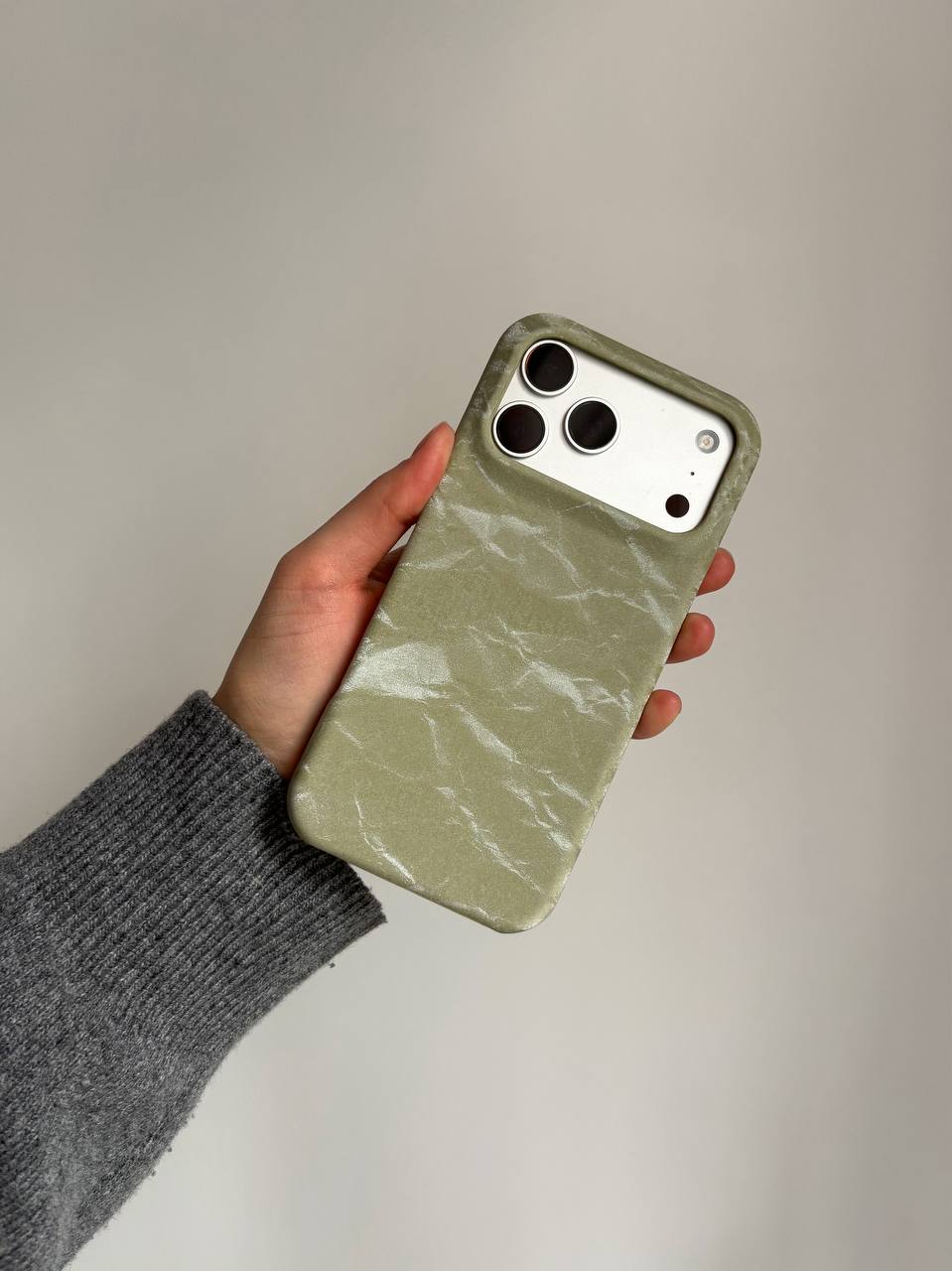 Оливковий чохол «Оксамит» на iPhone у руці в сірому рукаві